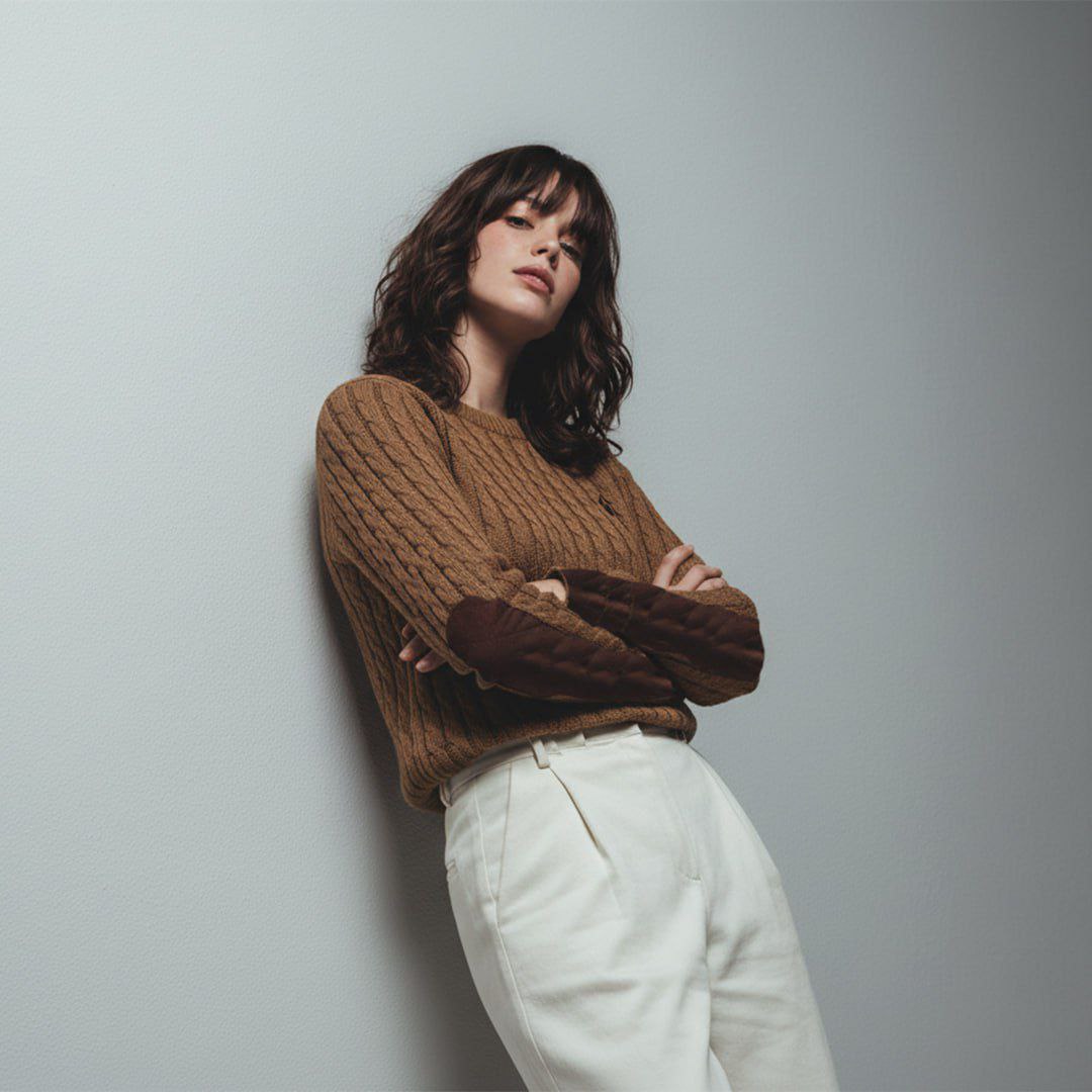 Woman wearing gold cable knit crewneck sweater